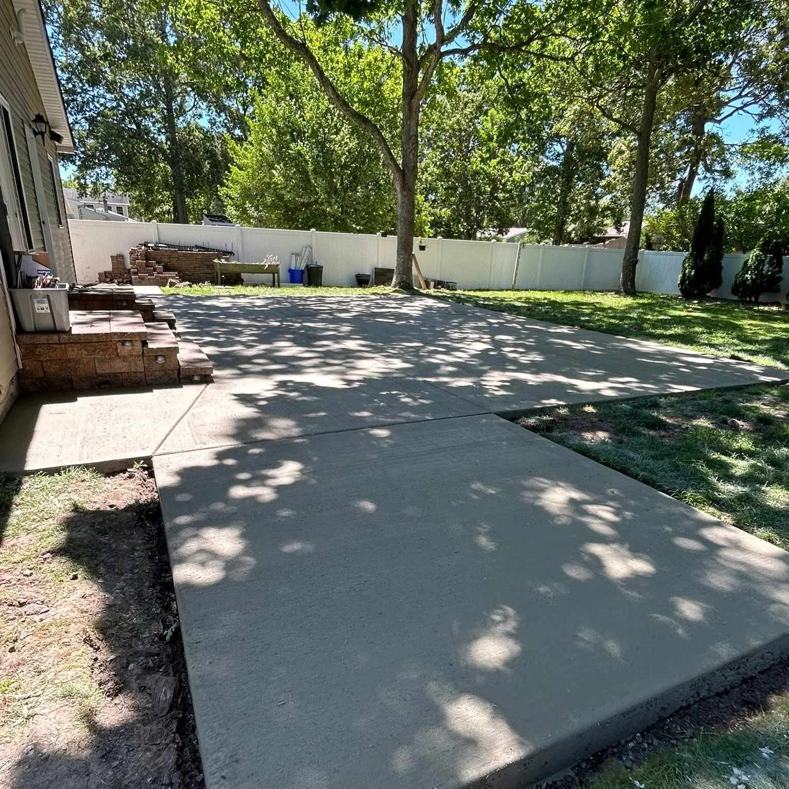 Large poured concrete patio in a fenced, tree-lined South Jersey backyard by D&R Services