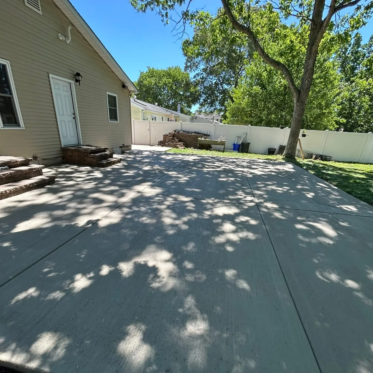 Backyard concrete patio with brick step landing installed by D&R Services in South Jersey